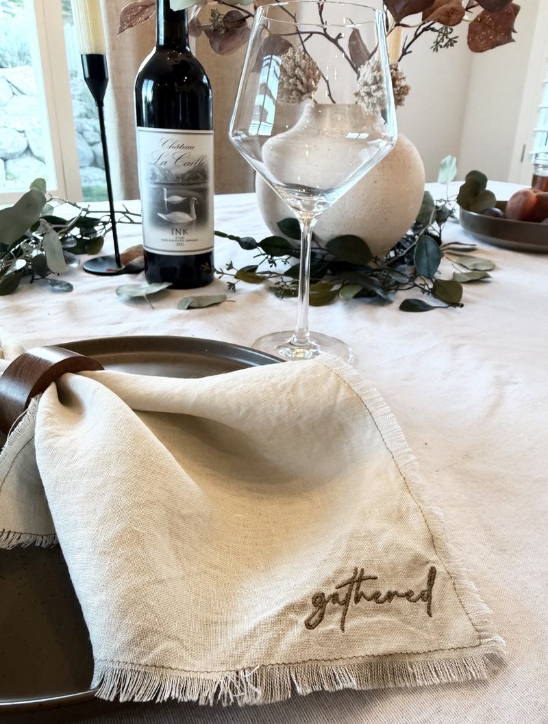 Gathered embroidered linen napkin in a leather napkin ring at a set table
