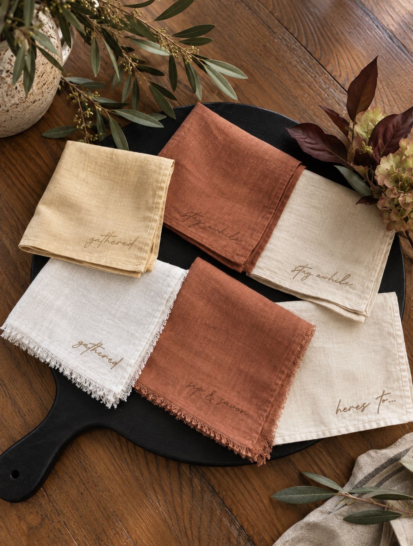 Embroidered linen napkins in rust, mustard, and oatmeal