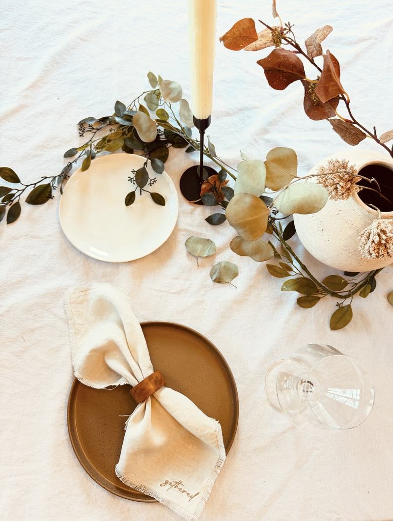 Gathered embroidered linen napkin folded on a stoneware plate